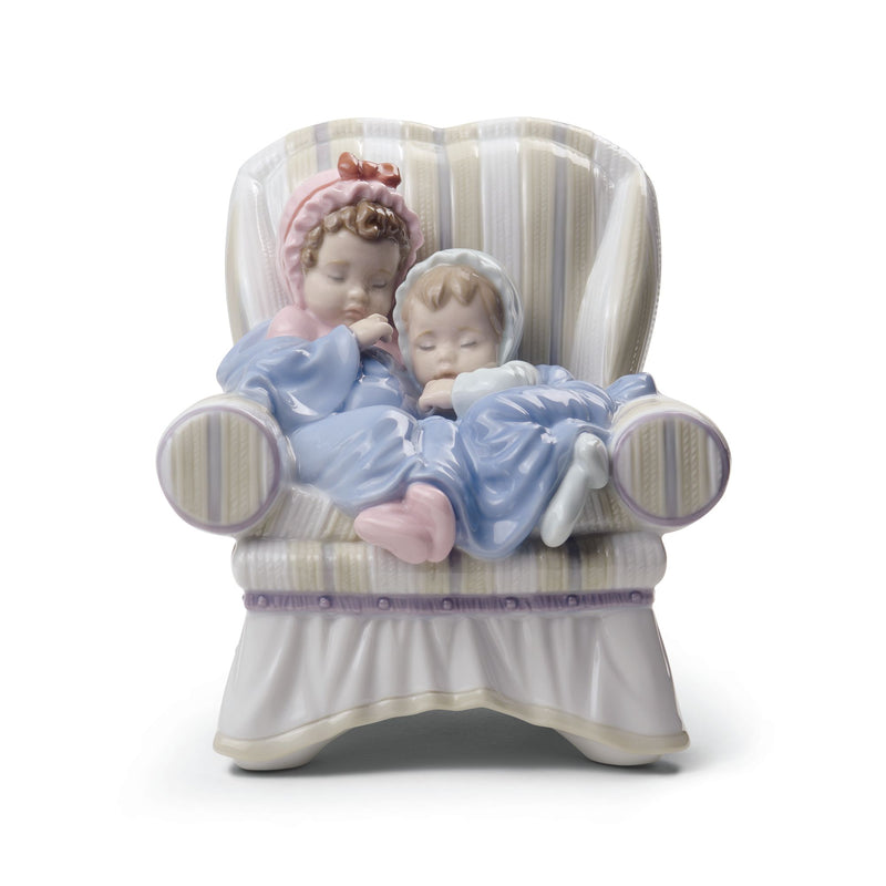 Porcelain figurine of two cherubs cuddled on a small upholstered chair, light blue and pink