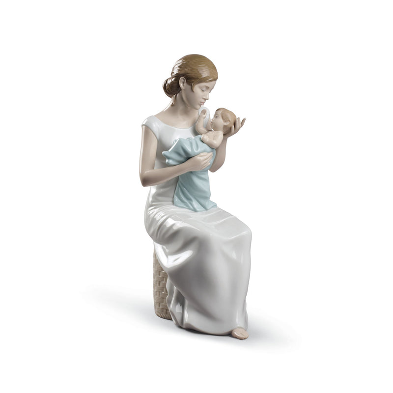 Porcelain figurine of a kneeling woman cradling a baby, light blue dress, white drapery