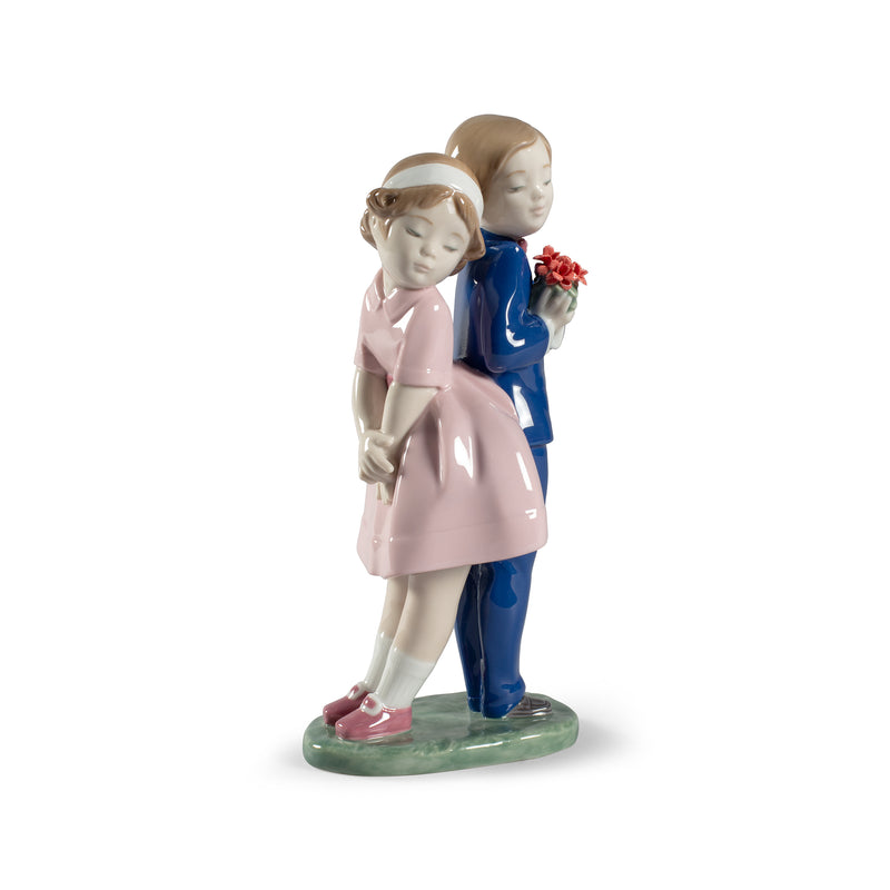 Porcelain figurine of two children, girl in pink dress and boy in blue suit, holding flowers