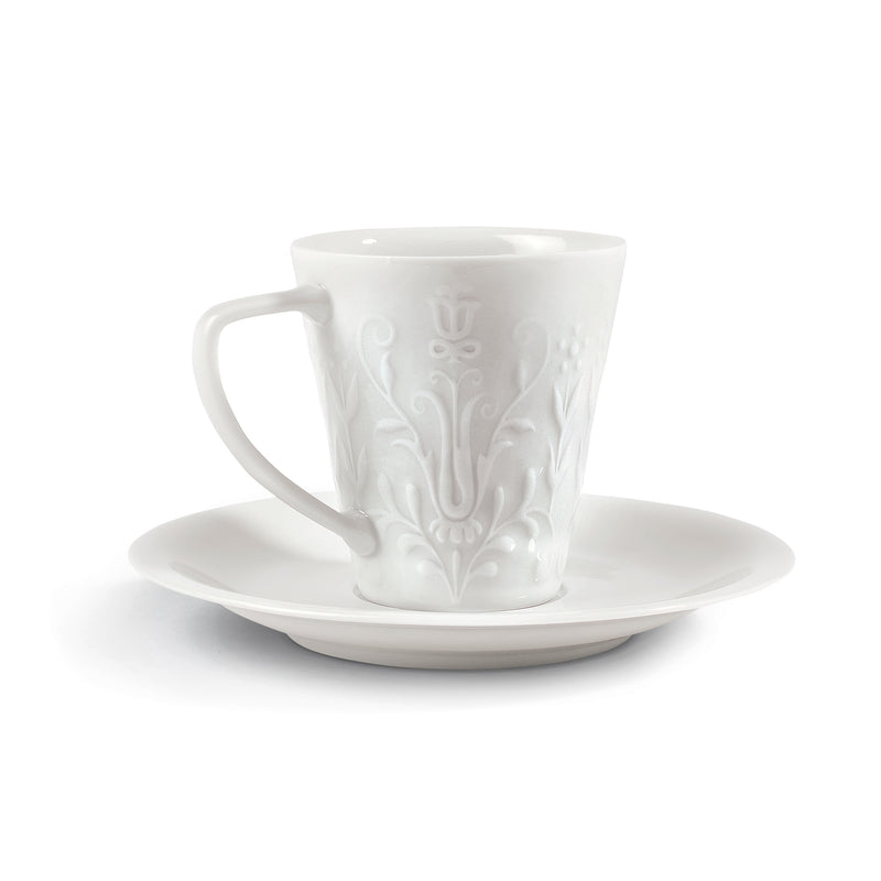White porcelain tea cup with embossed logo and matching saucer, handle on left