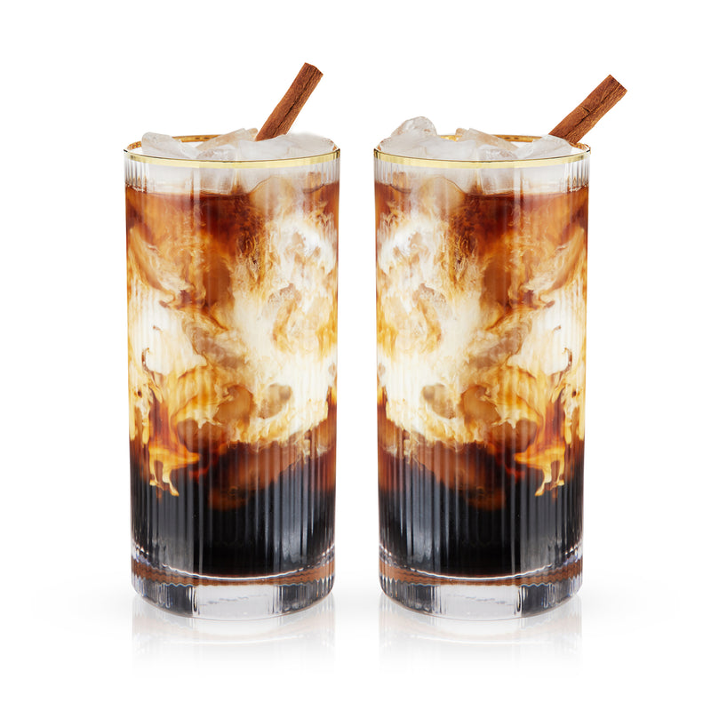 Set of 2 highball glasses with amber and dark layered drink, ice cubes, cinnamon stick