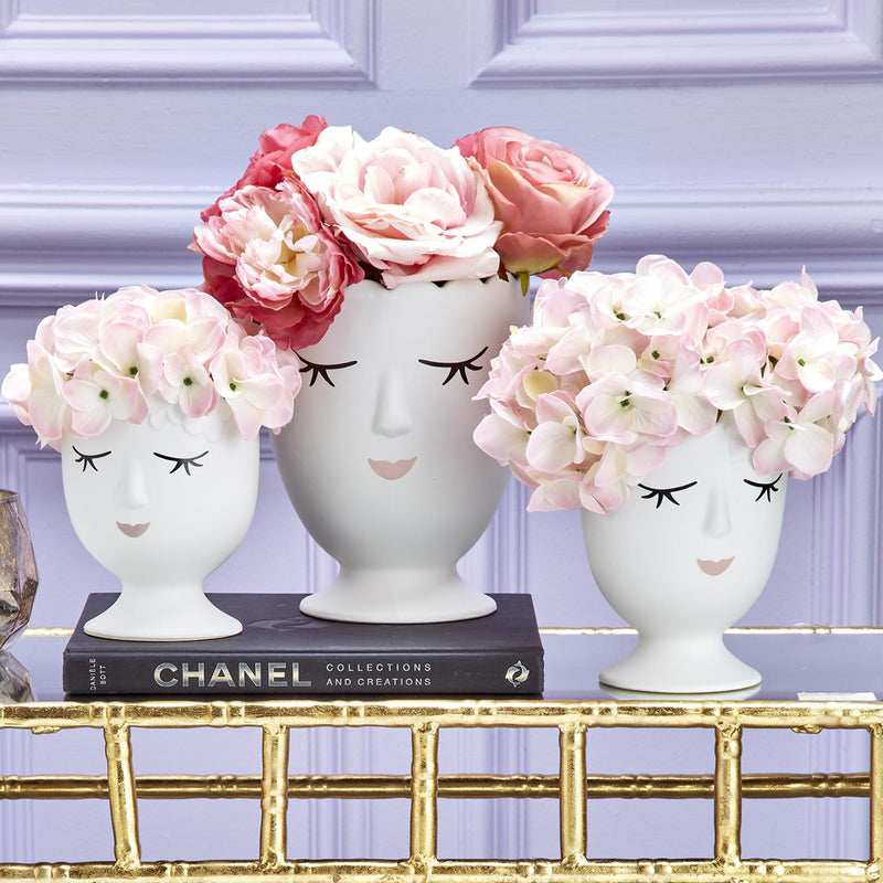 Set of 3 white porcelain face planters with flower-filled heads and pedestal bases