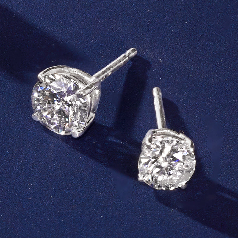Round diamond studs in 14kt white gold with prong-set center stones, close-up