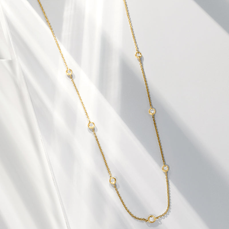 14kt yellow gold diamond station necklace, close-up of round bezel-set stones on chain