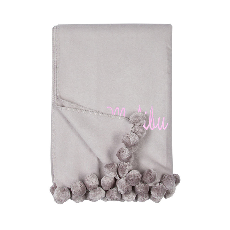 Gray throw blanket with pom-pom fringe and pink script monogram detail