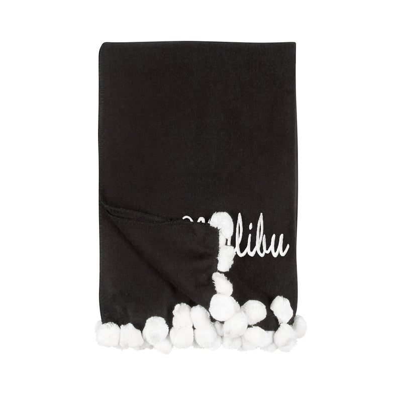 Black throw blanket with white pom pom trim and white script monogram