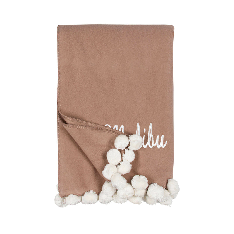 Tan throw blanket with white pom pom fringe and embroidered script monogram