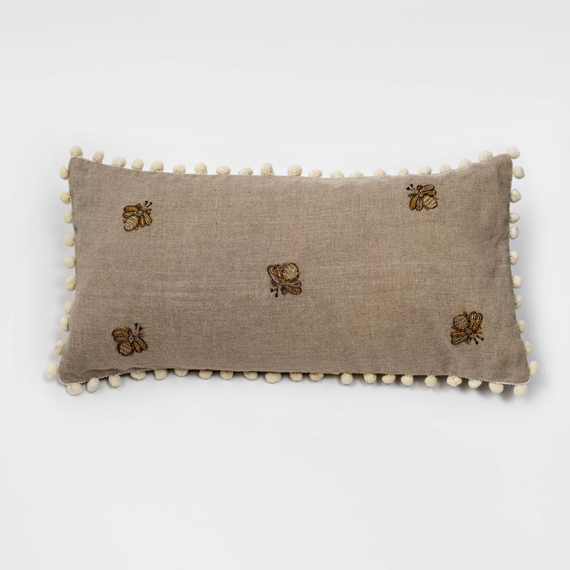 Taupe linen lumbar pillow with embroidered bees and cream pom pom trim