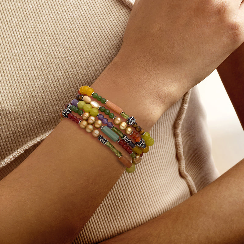 Multi-gemstone bead stretch bracelets on wrist with silver-tone beads and charms