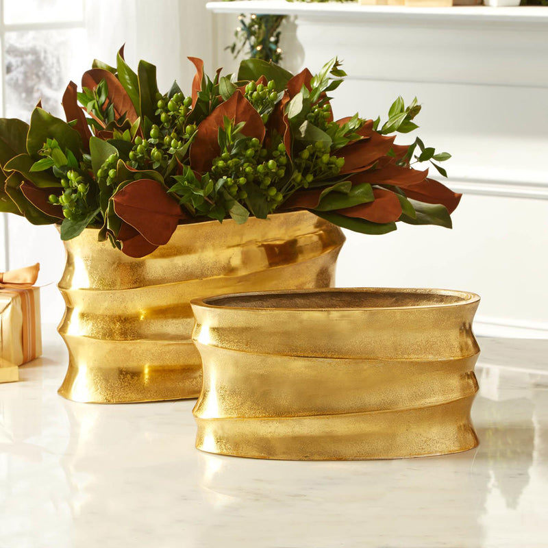Set of 2 golden aluminum wave planters with raised ridges, holding green and rust flowers