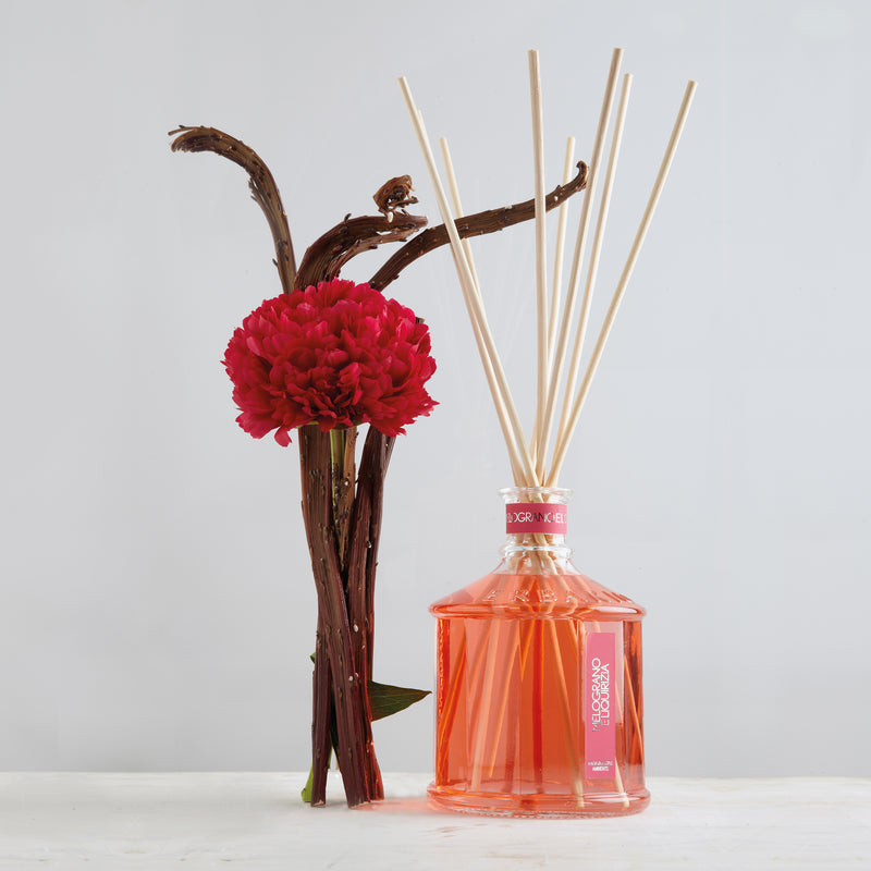 Pomegranate and liquorice scented diffuser bottle with reed sticks, clear glass and orange liquid