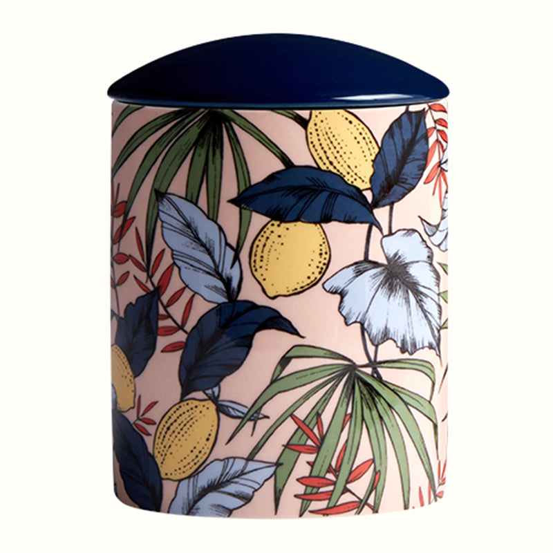 Large ceramic candle in cylindrical jar with tropical leaf and fruit pattern, dark lid