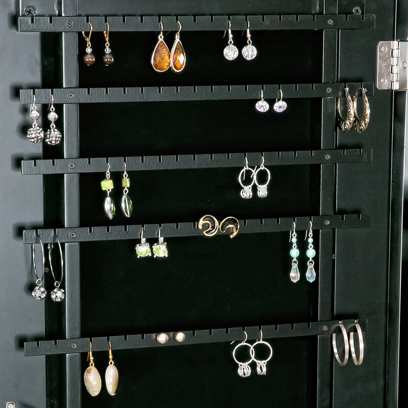 Black velvet jewelry armoire back with multiple earrings hanging on hooks