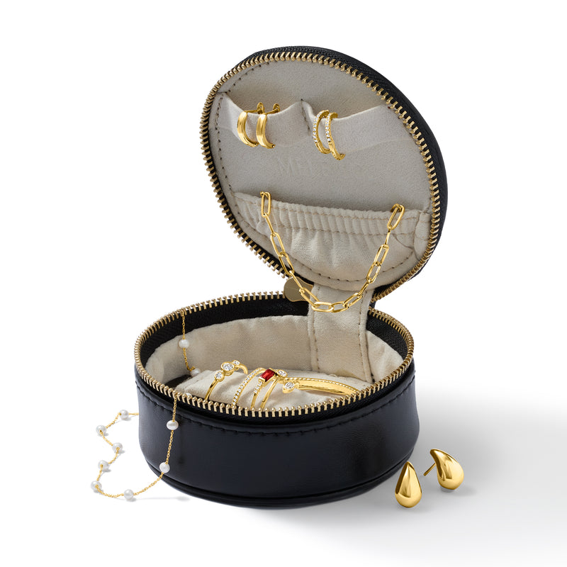 Black round travel jewelry box open with cream lining, displayed earrings, necklace and chain hooks