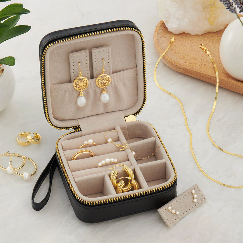 Black faux leather jewelry travel case open with beige organizer pads for earrings and rings