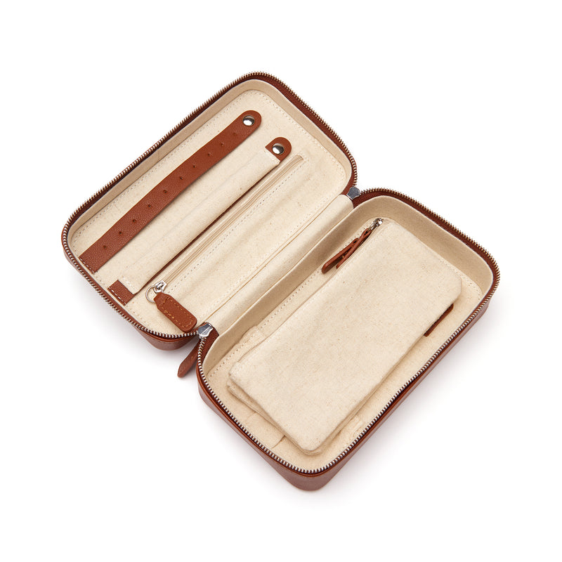 Brown faux leather travel jewelry case, open with straps and zippered cream compartments