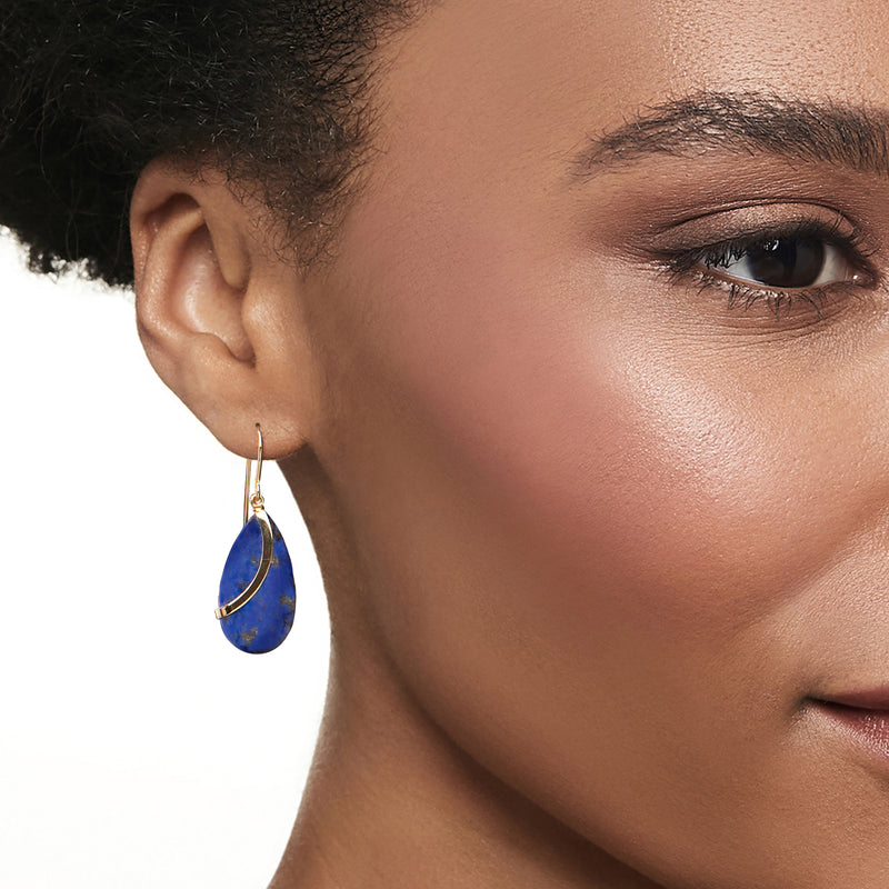 Teardrop blue lapis drop earring on ear with yellow gold ear wire