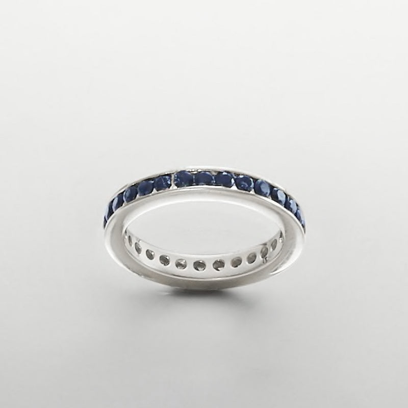 Sterling silver eternity band with dark blue stones around the edge and smooth inner band.