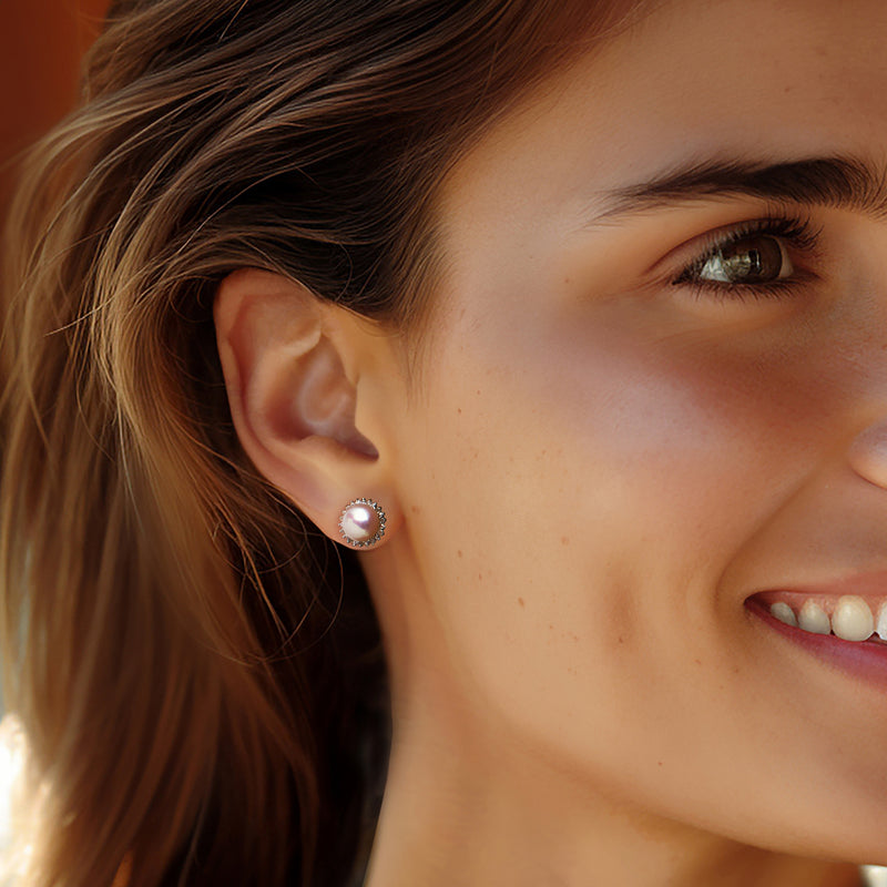 Pearl stud earrings in sterling silver with diamond halo, worn on ear