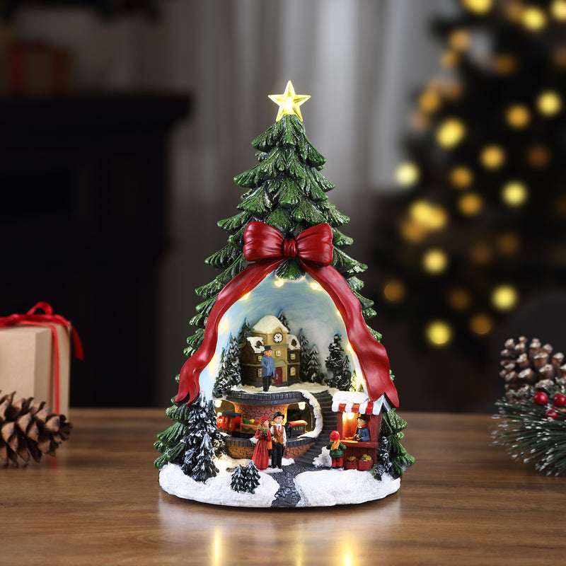 Decorated musical village tree ornament with star topper, red bow, and village scene