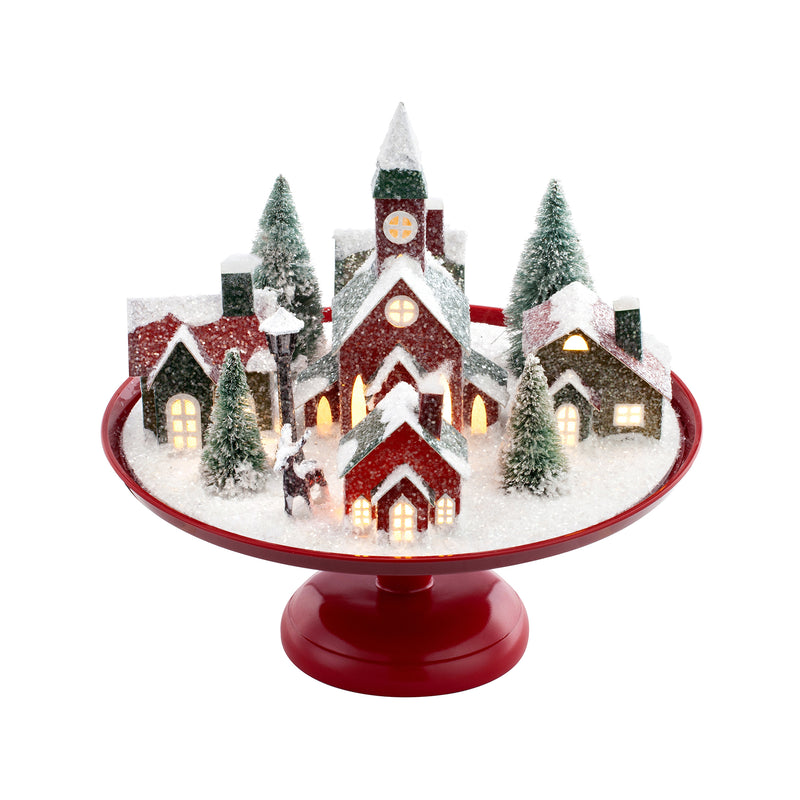 Nostalgic paper village set with lit houses and evergreen trees on red iron platter