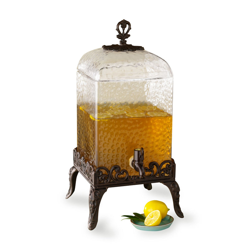 Vintage-style beverage dispenser with glass jar, amber spigot tap, and ornate dark metal stand