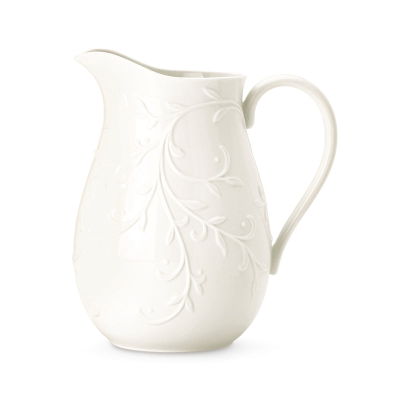 White ceramic pitcher with embossed floral design and curved handle