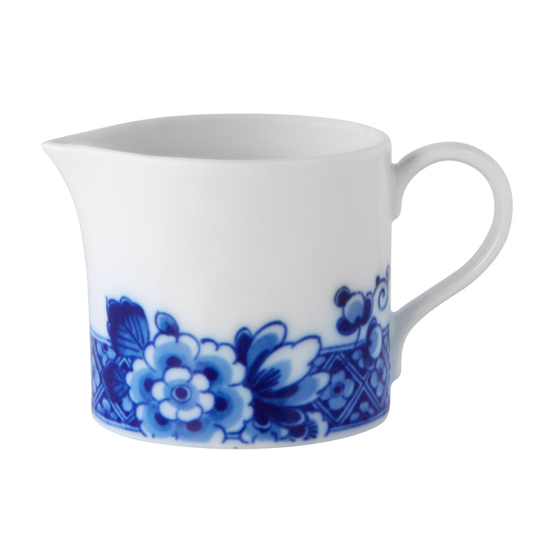 Porcelain creamer in cream with blue floral pattern and curved handle
