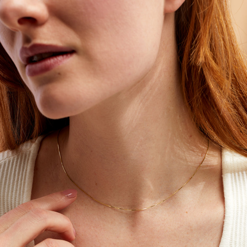 14kt yellow gold box-chain necklace on model, thin .6mm links at neckline