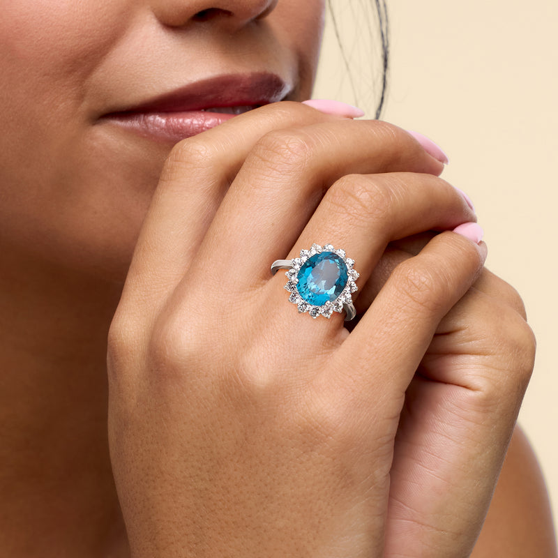 Sterling silver oval London blue topaz ring with white halo worn on hand
