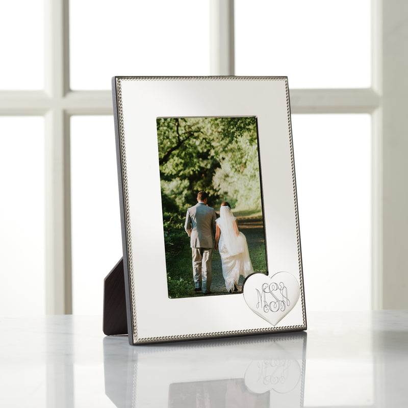 Silver textured picture frame with heart monogram corner and hinged stand, holding a photo.