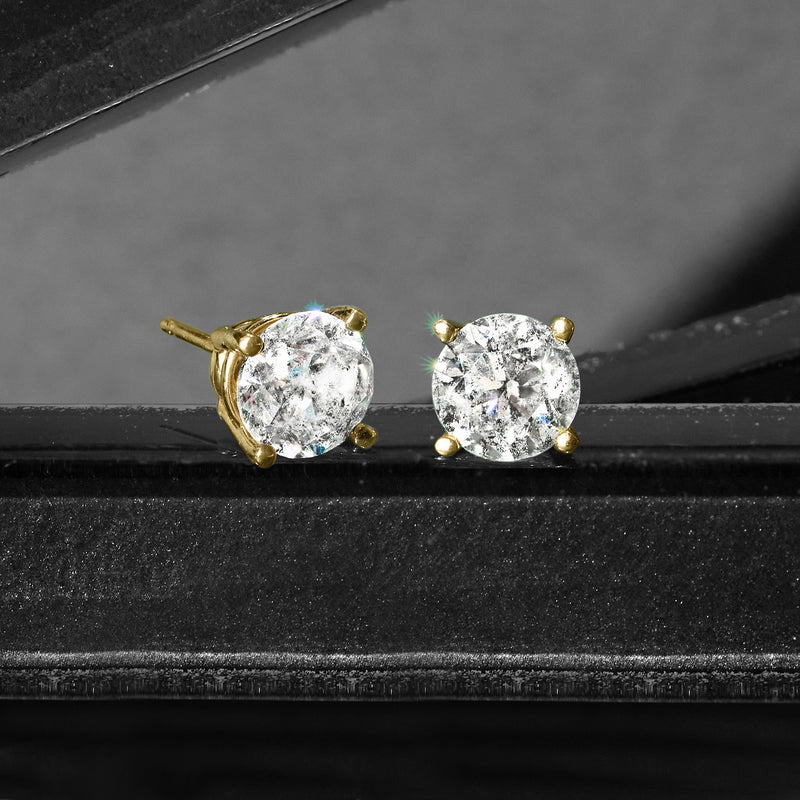 Diamond stud earrings with 14kt yellow gold prongs, close-up view