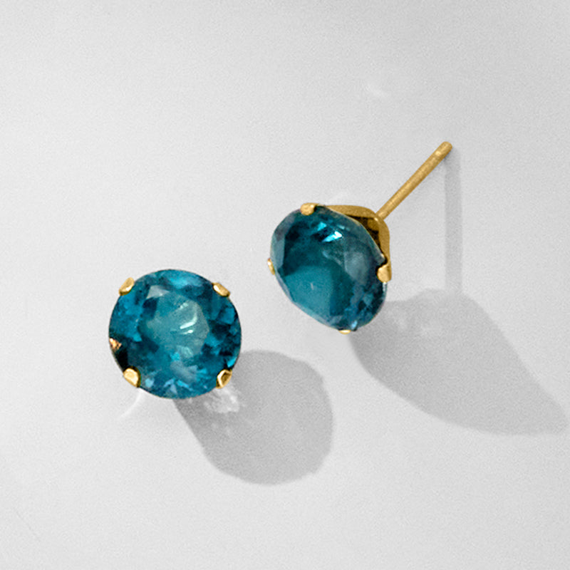 Close-up London blue topaz stud earrings, gold prong settings with round blue stones