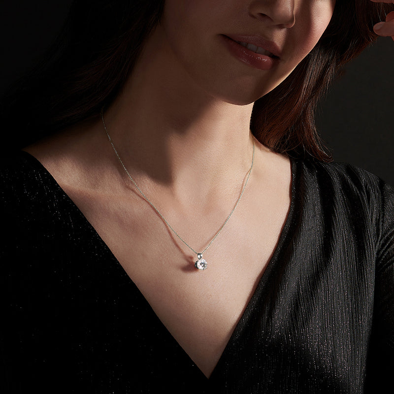 Round CZ solitaire pendant necklace in white gold on a model's neckline