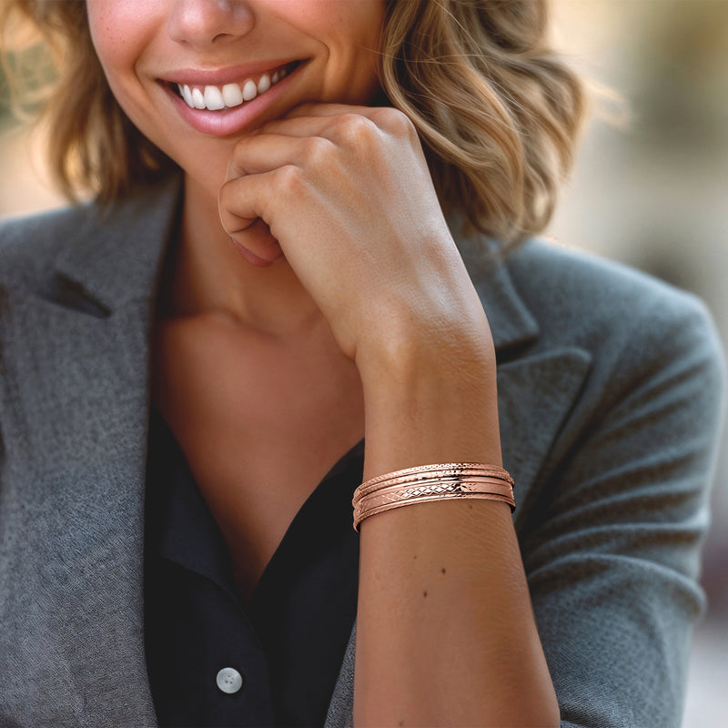 Rose gold five-bangle bracelet set on wrist with mixed textured braided cuffs
