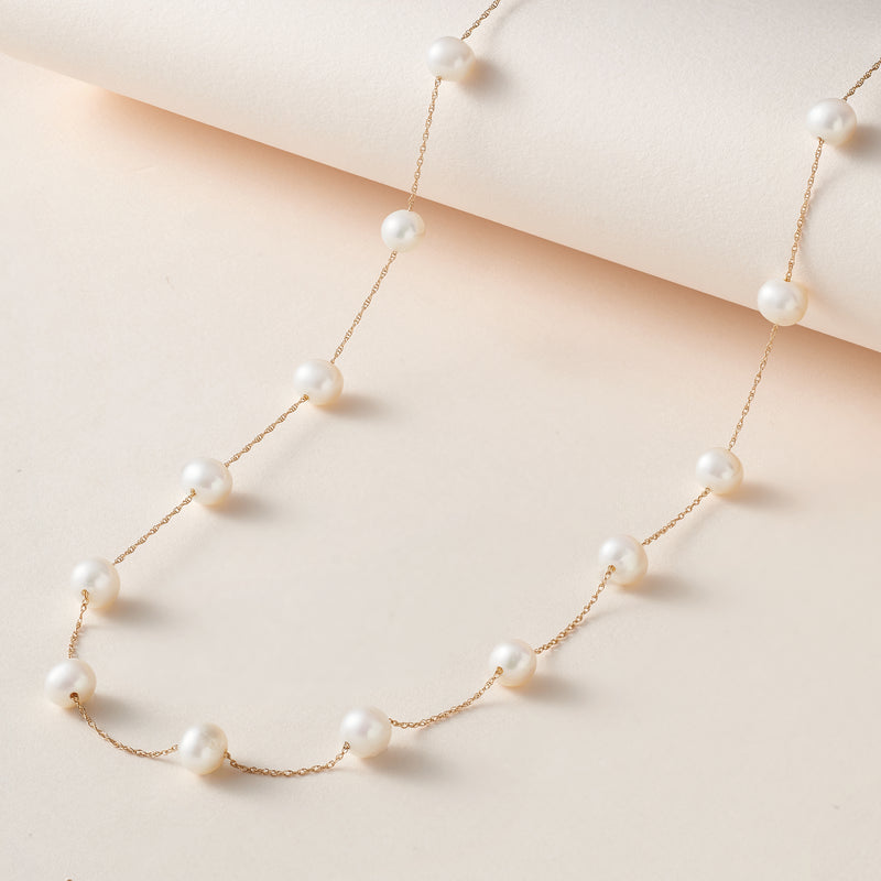 14kt yellow gold cultured pearl station necklace with round white pearls, flat lay
