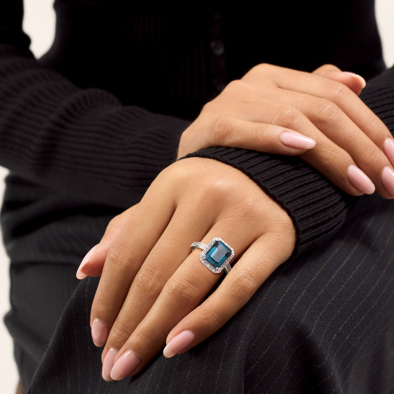 Sterling silver ring on hand with cushion-cut blue topaz and small diamond accents