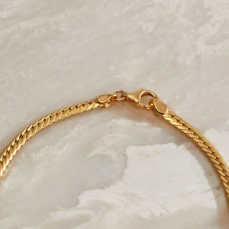 Yellow gold necklace clasp and jump ring on graduated Cuban-link chain.