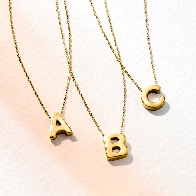 Yellow gold mini initial necklaces with A, B, and C pendants on fine chains