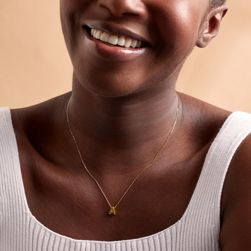 Yellow gold mini initial A necklace pendant on a fine chain at the neckline