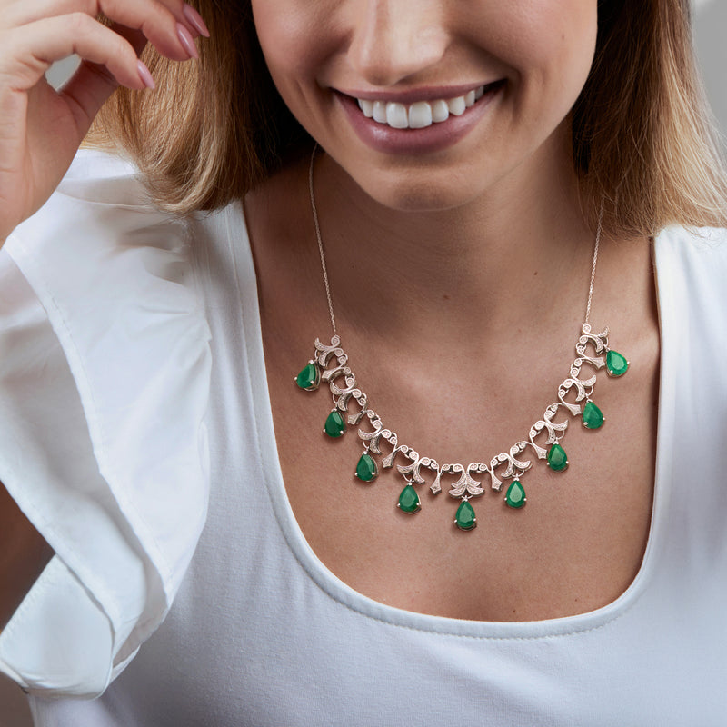 Sterling silver necklace worn by model: emerald-green teardrop stones with diamond links