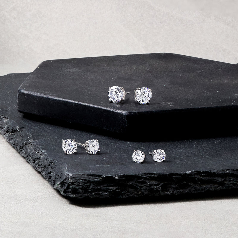 Six CZ stud earrings on dark slate, round clear stones in silver settings