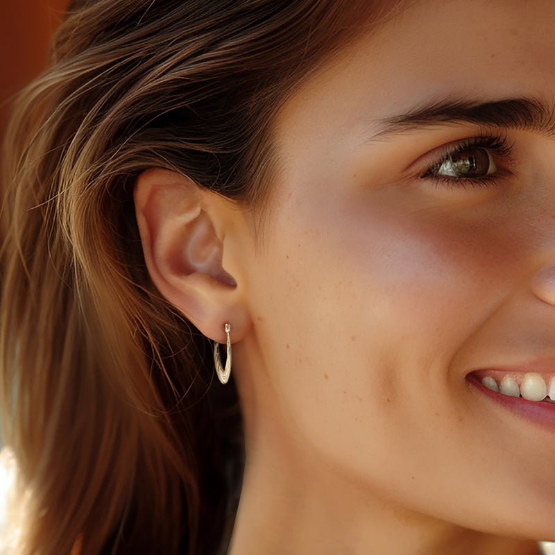 Twisted hoop earrings in 14kt yellow gold worn on a model’s ear