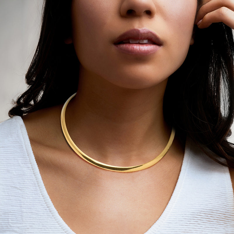 Gold-tone omega necklace worn on model’s neck, slim mesh cable chain