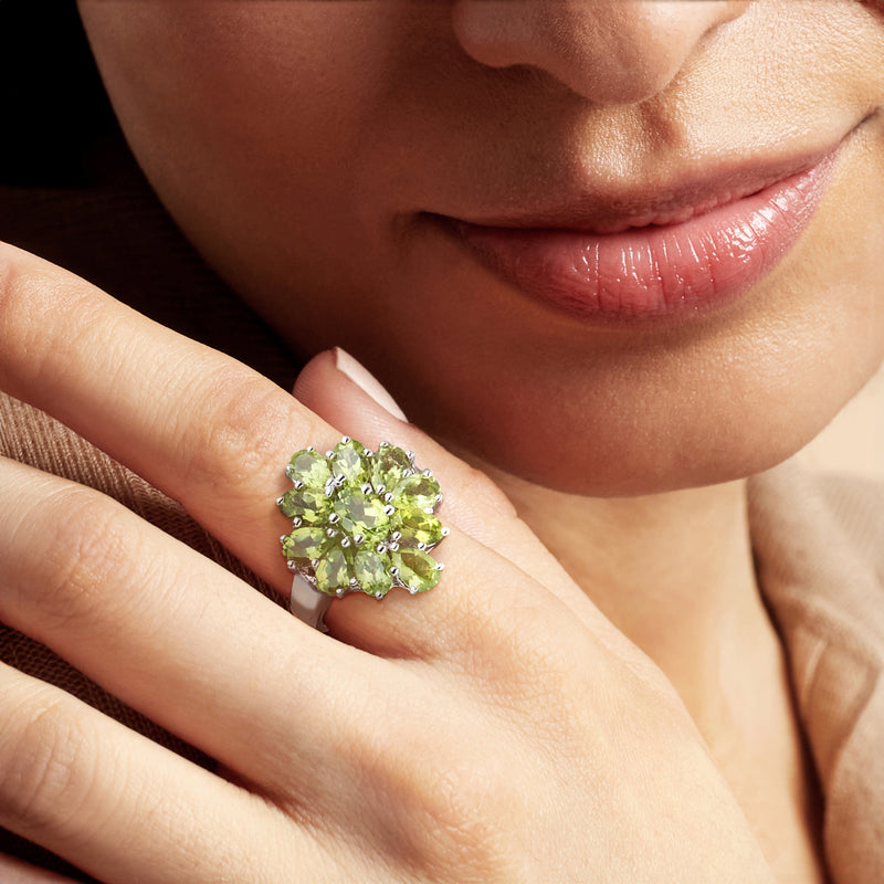Peridot cluster ring on hand in sterling silver with oval green stones and prong settings