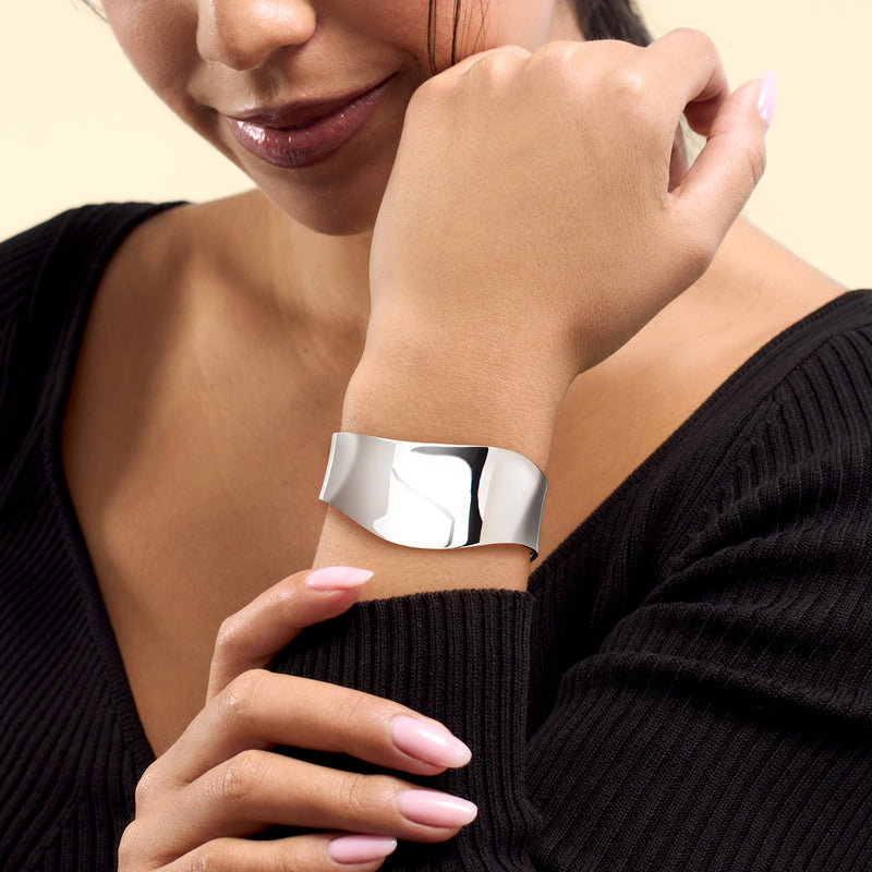 Sterling silver wave cuff bracelet worn on wrist, polished wide band