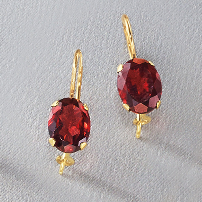 Close-up of gold earwire drop earrings with round faceted red garnet and prong settings