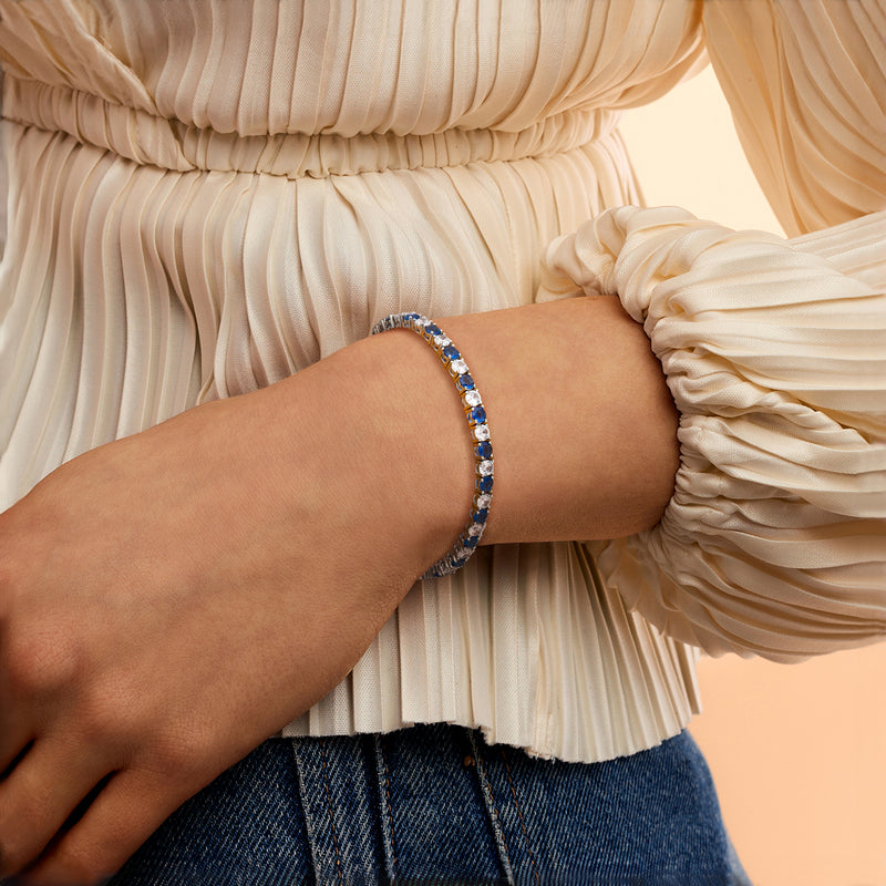 Blue-stone tennis bracelet on wrist with sterling silver setting and clear CZ accents