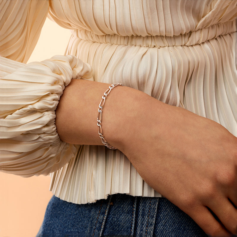 Two-tone figaro-link bracelet on wrist, rose gold over sterling with silver links