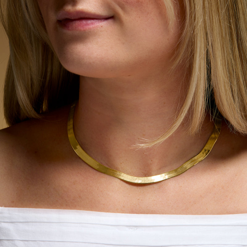 Gold herringbone necklace worn close to the base of the neck